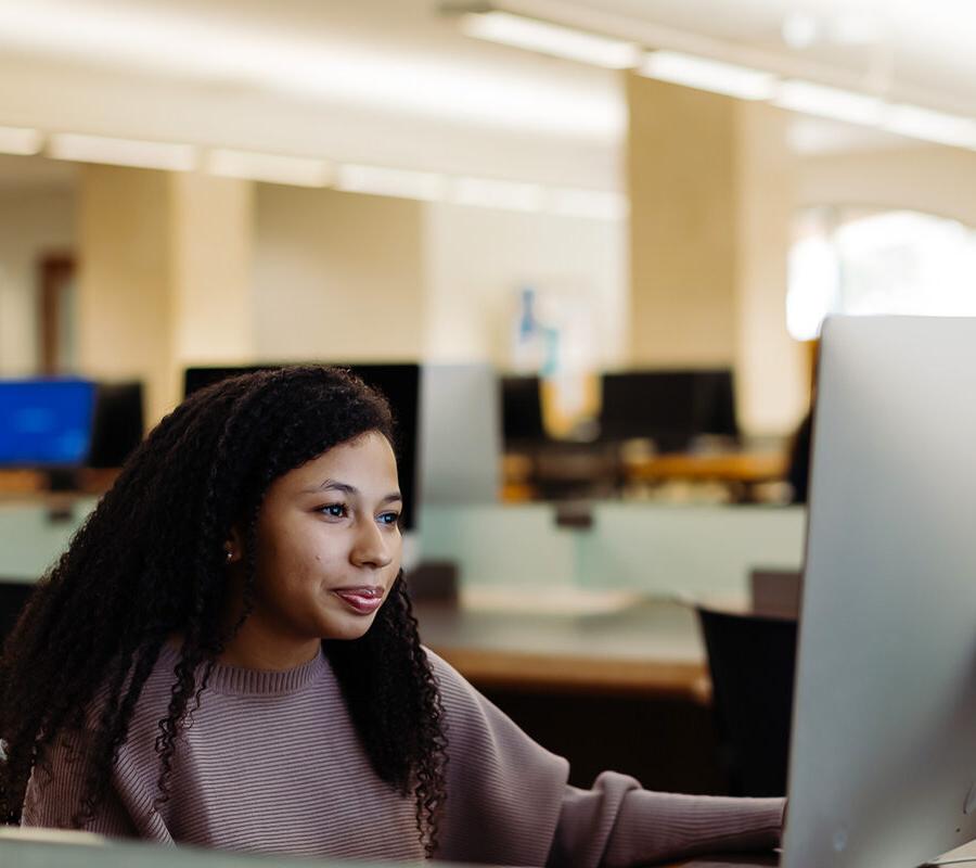 graphic arts and graphic design student uses a computer in the library.